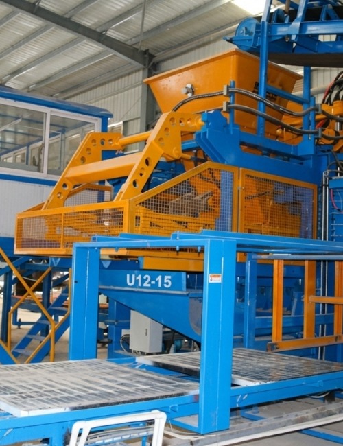 U12-15 Pallet-Free Block Machine in Industrial Production Line U12-15 pallet-free concrete block making machine installed in an industrial factory, showing hopper, safety guarding, and automated production platform.