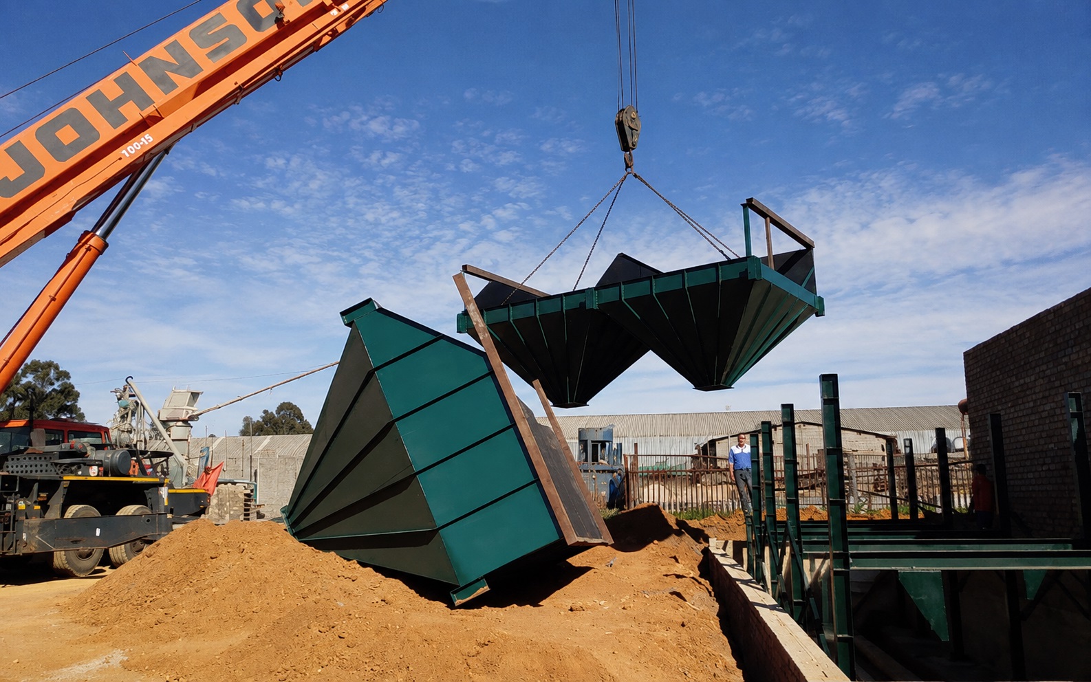 A green plant hopper is lowered by crane into a steel installation frame during a PJR Engineering machinery project.